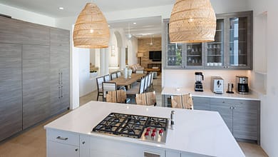 مطابخ مودرن يتميز بتصميم مفتوح وأنيق مع إضاءة طبيعية وخزائن خشبية فاتحة وأجهزة مدمجة